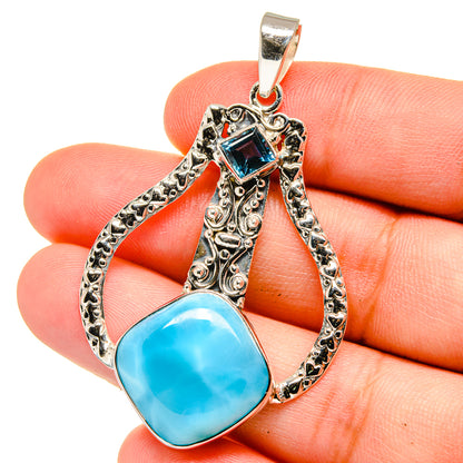 Sterling silver pendant with blue teardrop stone, ornate filigree and bail.