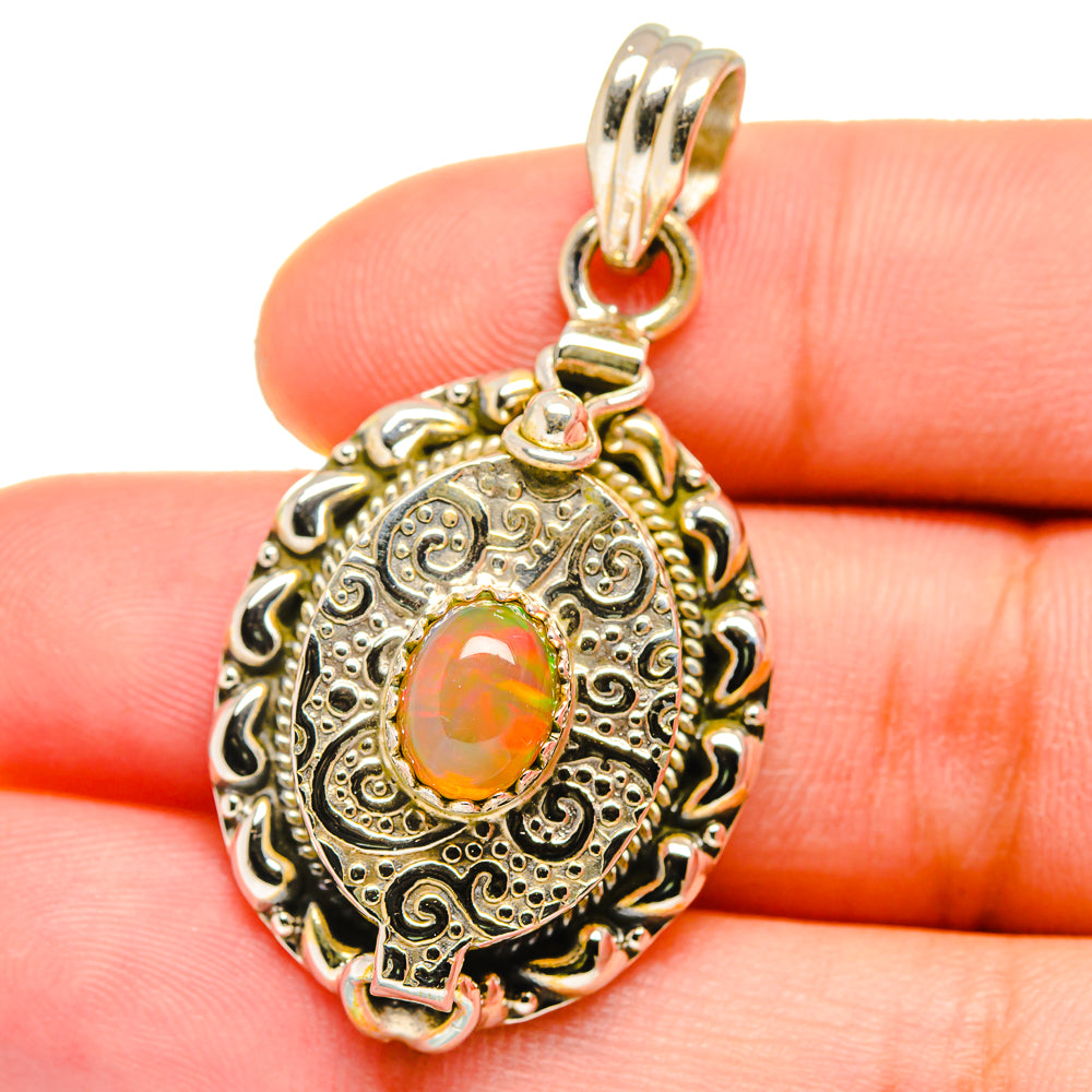 Ornate oval opal pendant close-up, orange center stone and loop bail in silver setting
