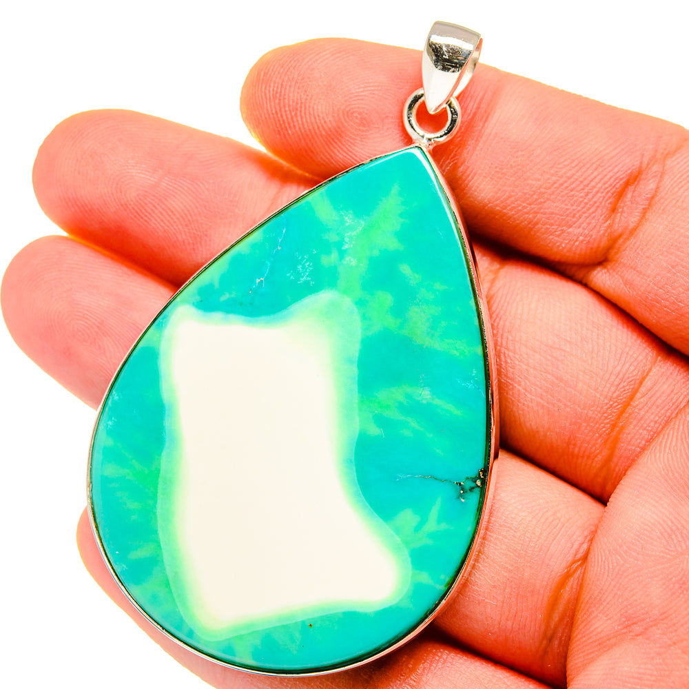 Turquoise teardrop howlite pendant in silver setting, held in open hand