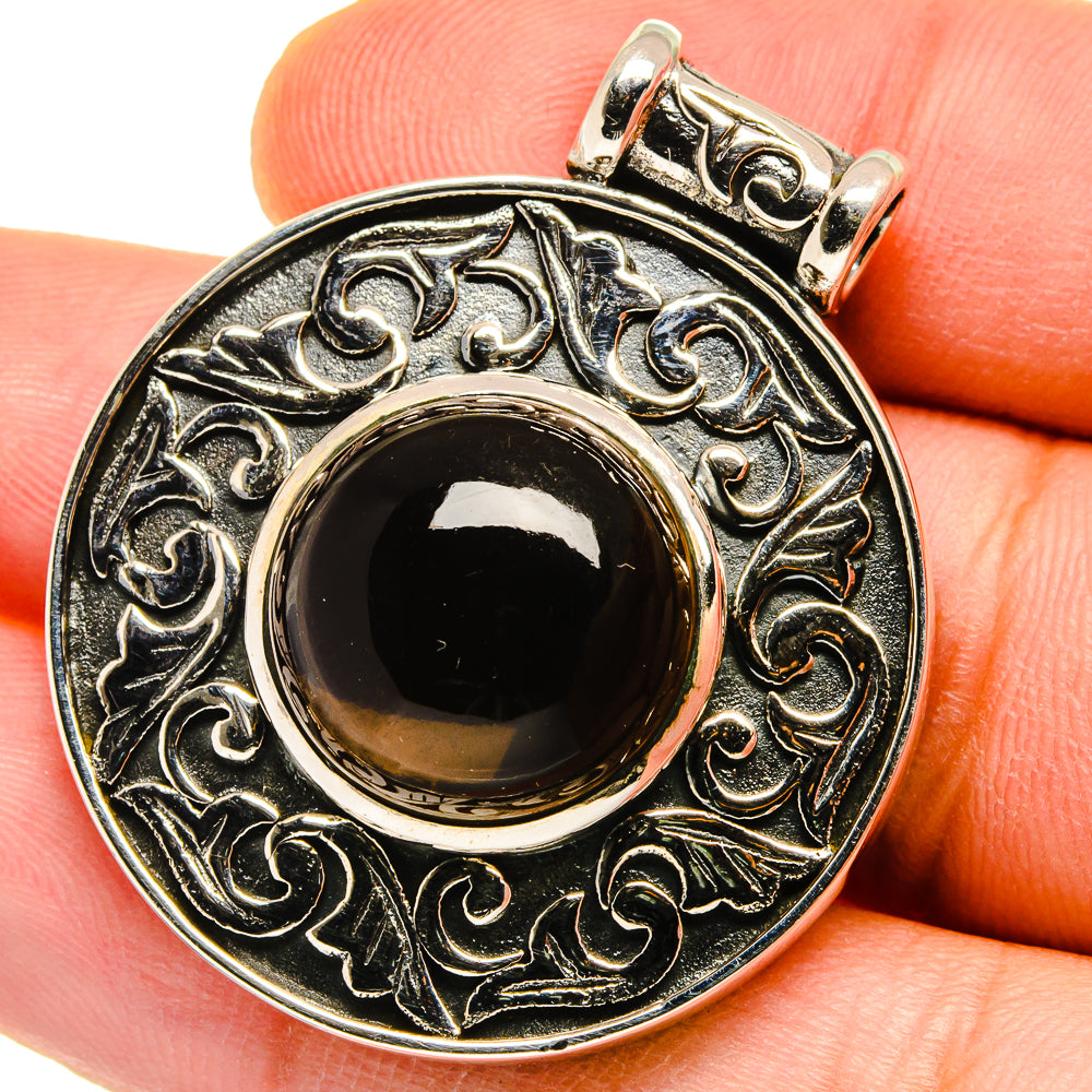 Sterling silver pendant with ornate bezel and round dark cabochon, top bail