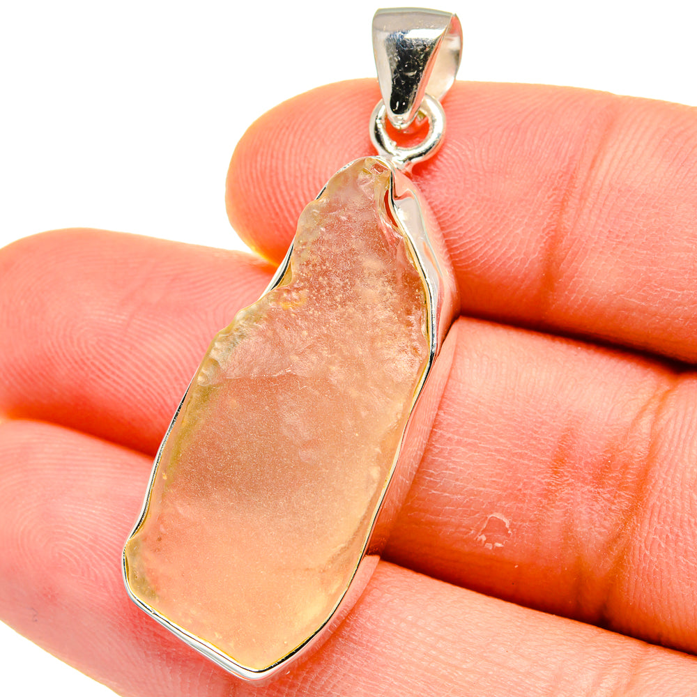 Sterling silver pendant with irregular amber desert glass cabochon on fingertip
