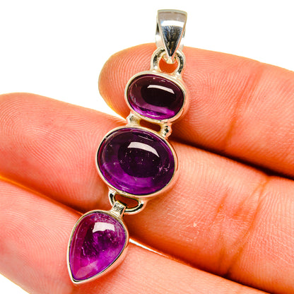 Amethyst pendant close-up on hand, three purple gemstones in silver bezel settings