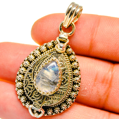 Close-up gold-tone teardrop pendant with filigree border, oval iridescent moonstone
