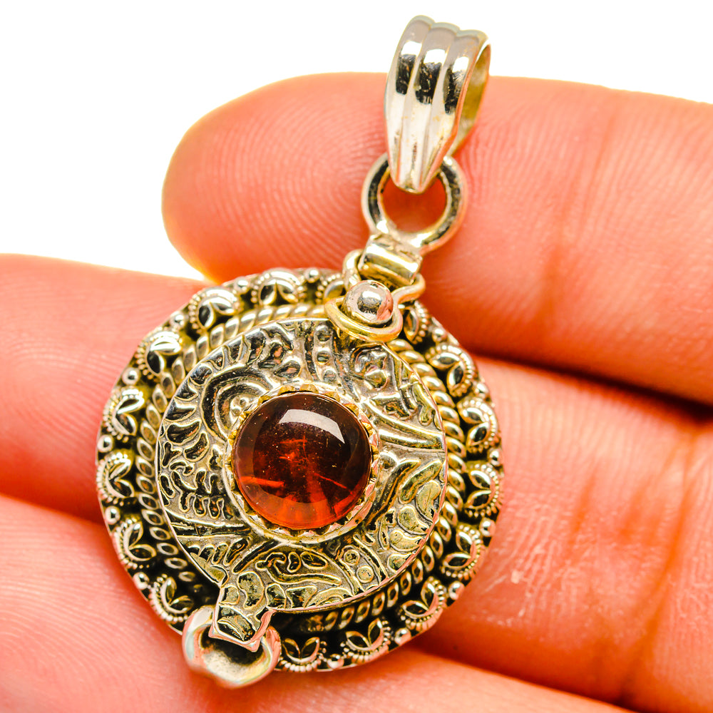 Poison pendant close-up: red round stone in engraved oval frame with silver bail