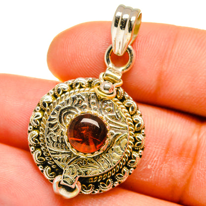 Poison pendant close-up: red round stone in engraved oval frame with silver bail