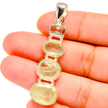 Silver pendant with four round green gemstones in bezel settings, top bail visible