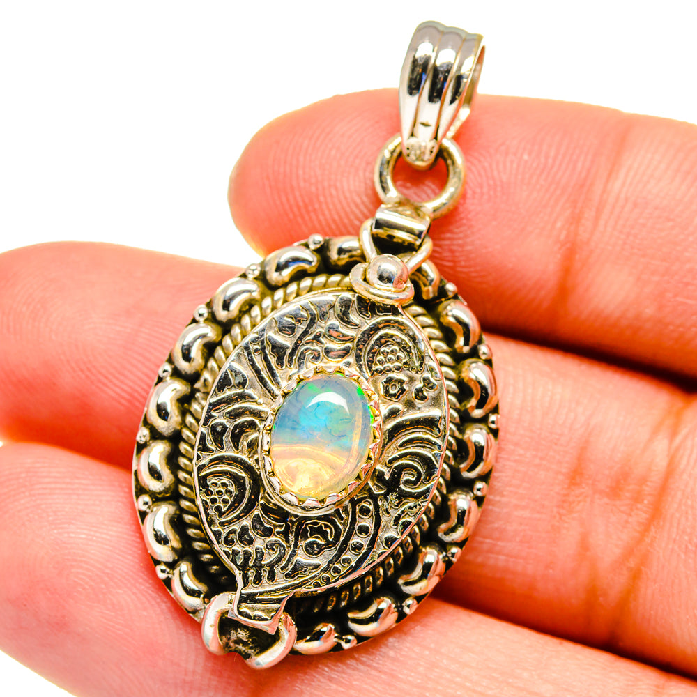 Oval Ethiopian opal charm pendant in detailed silver-tone round bezel filigree