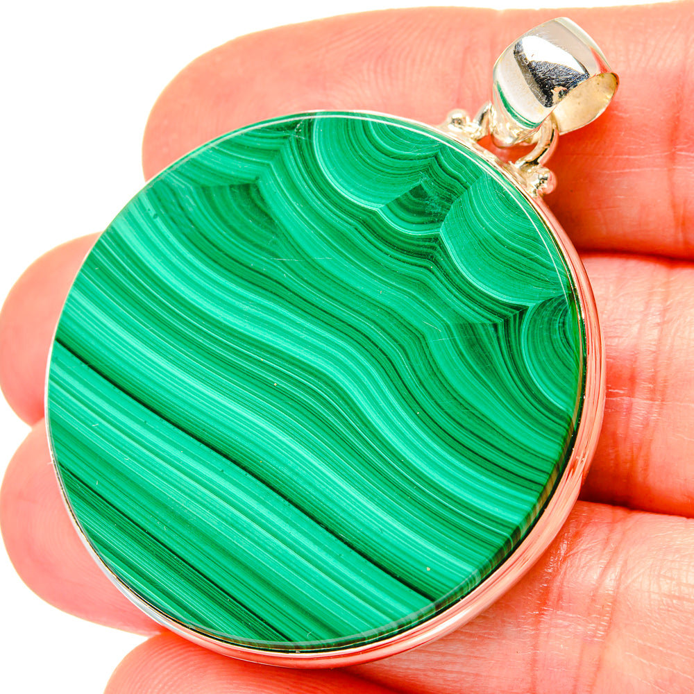 Round malachite pendant held in hand, green stone in 925 sterling silver bezel