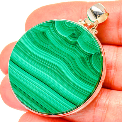Round malachite pendant held in hand, green stone in 925 sterling silver bezel