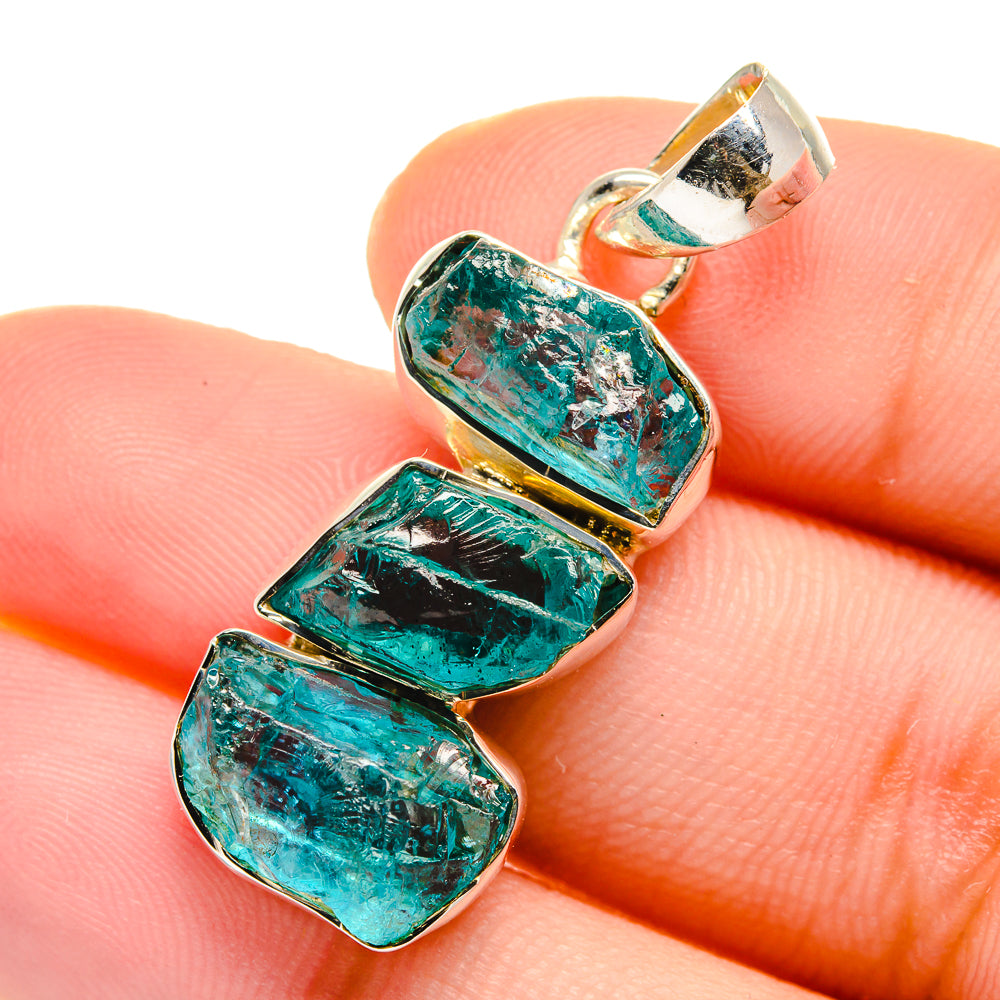 Close-up rough apatite pendant on finger, teal stone rectangles in silver bezel