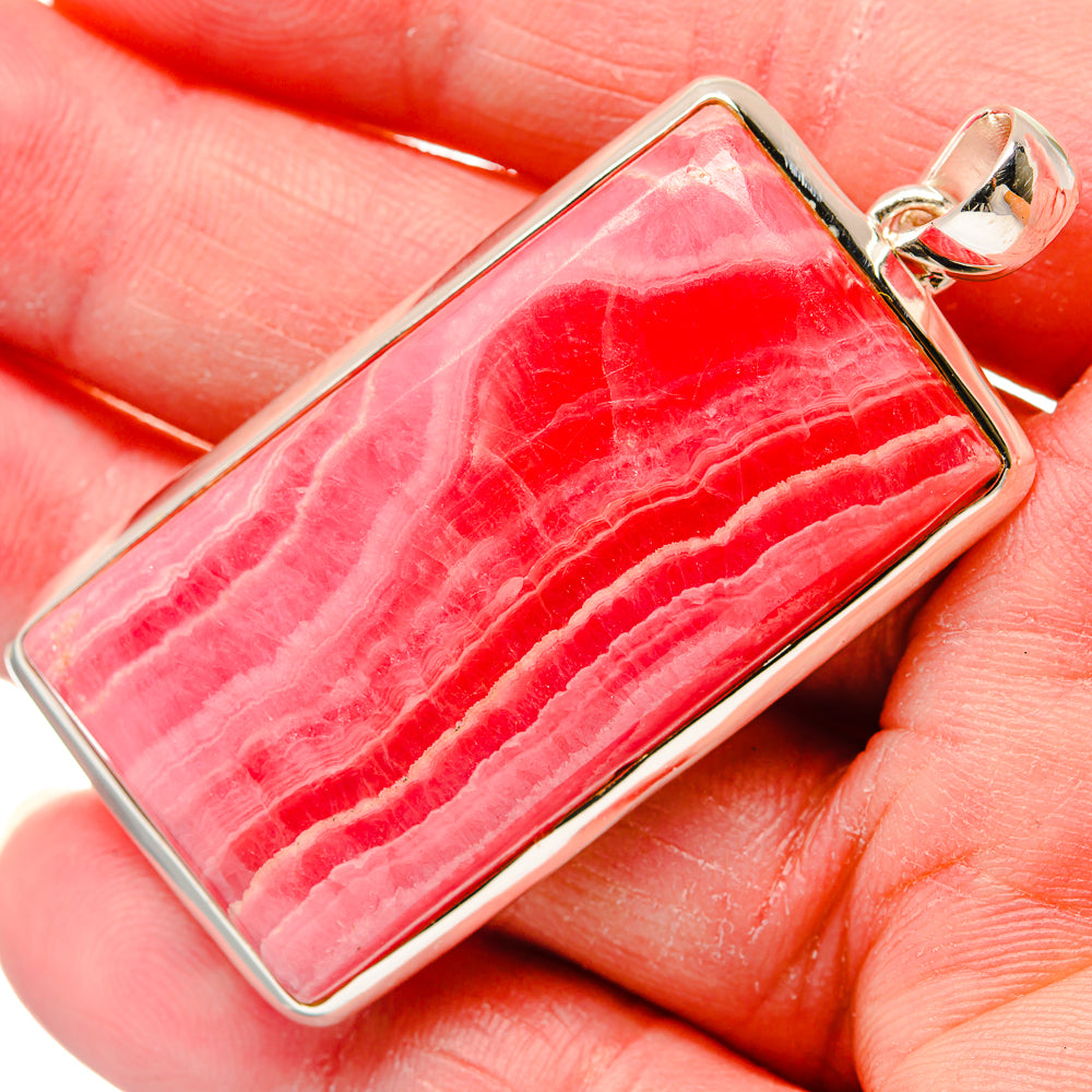 Rectangular red rhodochrosite pendant with silver loop bail, close-up on stone