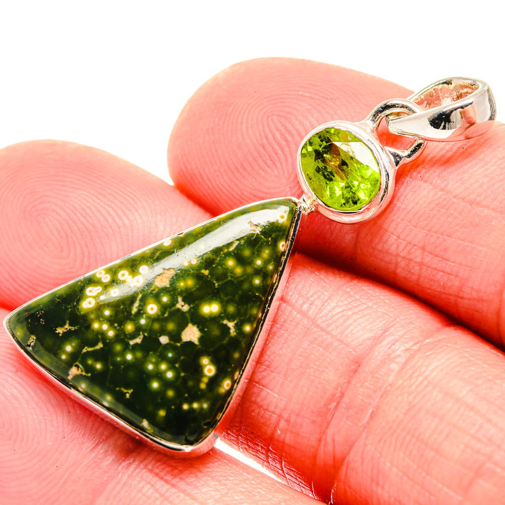 Round green peridot and triangular ocean jasper pendant in silver bezel, close-up