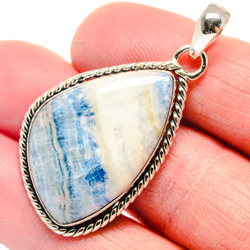Blue scheelite teardrop pendant with braided border and silver loop bail, close-up
