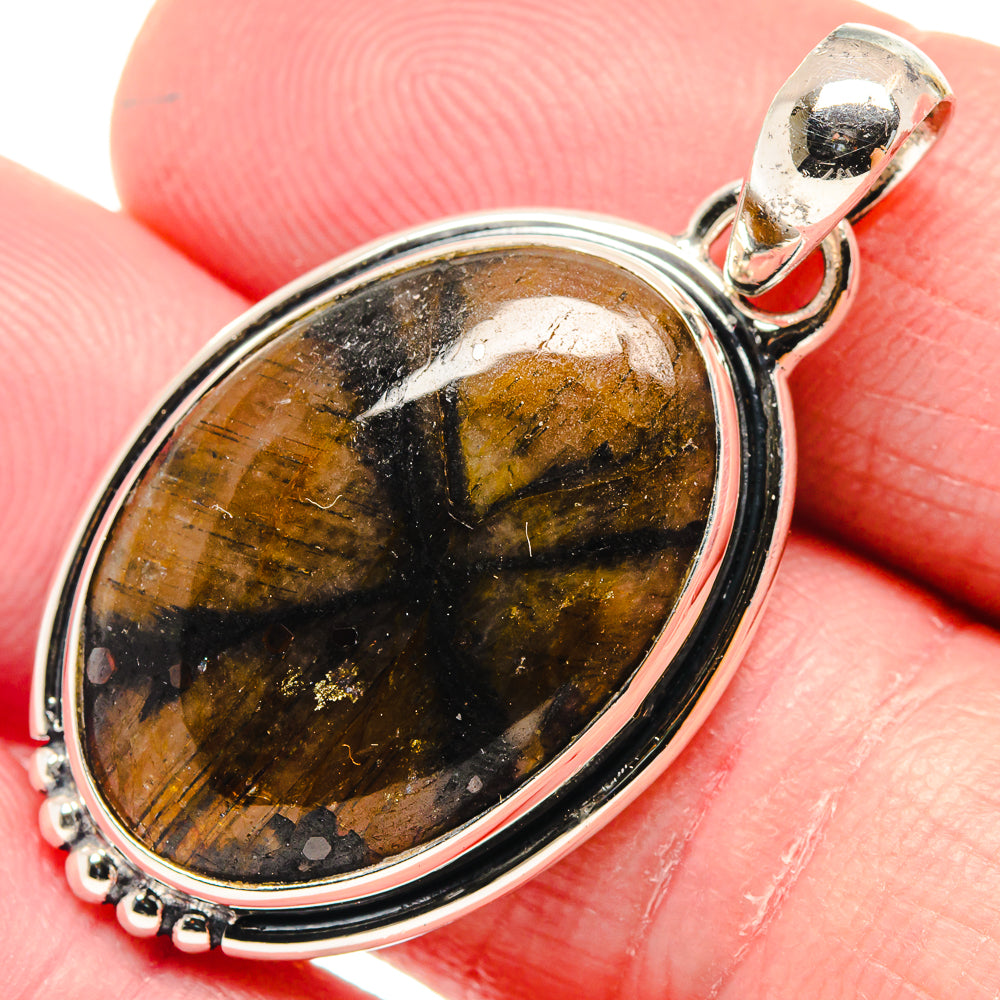 Chiastolite pendant with oval amber-and-black stone bezel and silver bail, close-up