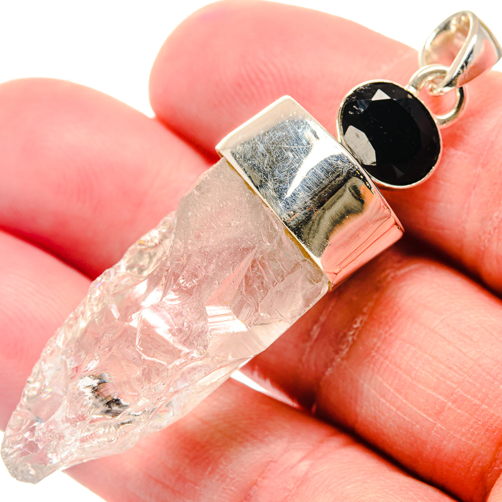 Close-up of silver bezel setting holding clear crystal and black oval onyx with bail