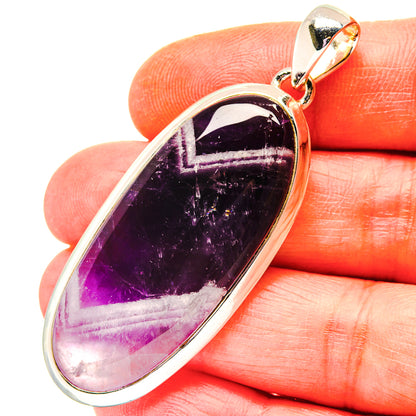 Sterling silver amethyst pendant with dark purple elongated oval stone and bail loop.