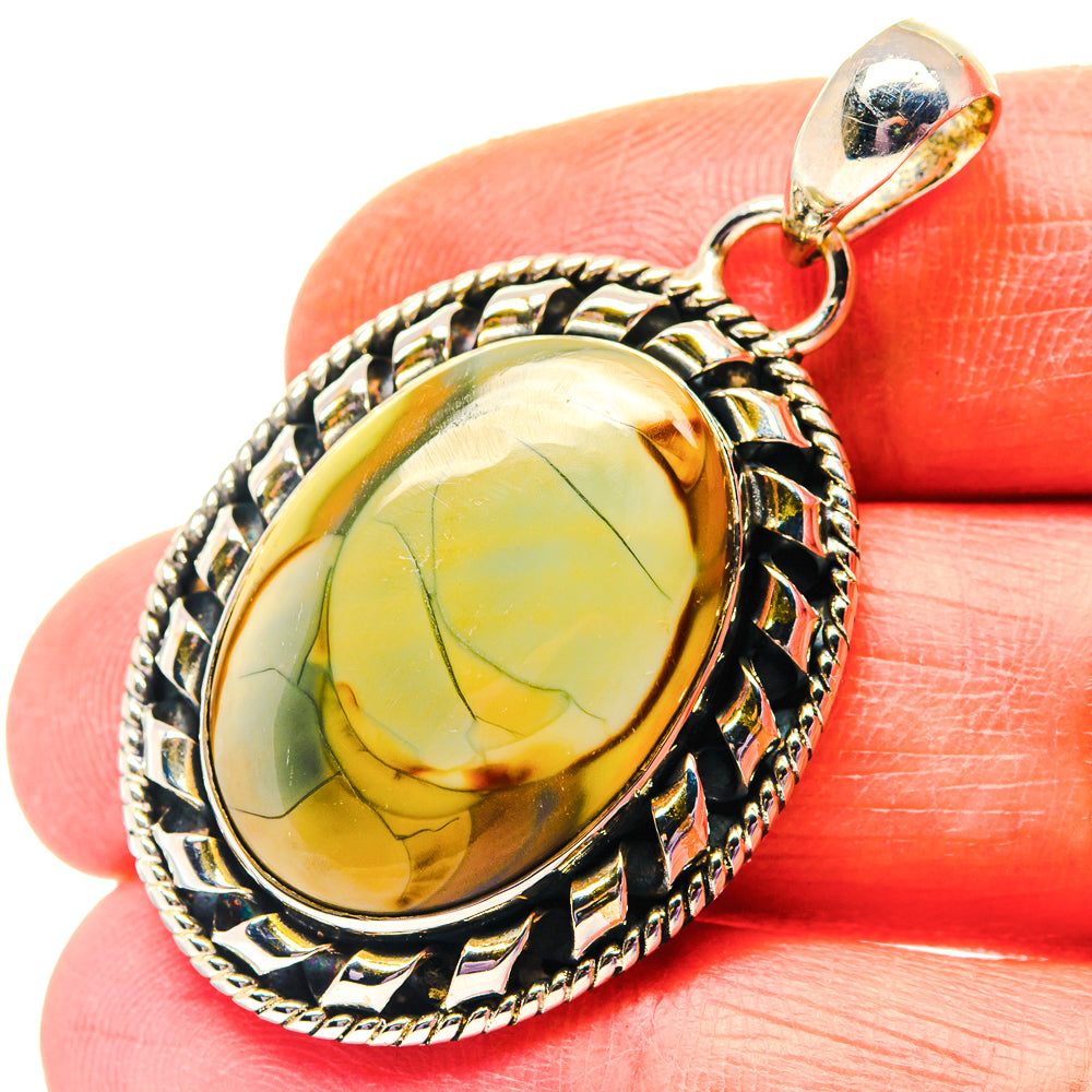 Oval yellow-green jasper pendant with ornate sterling silver frame and round bail.