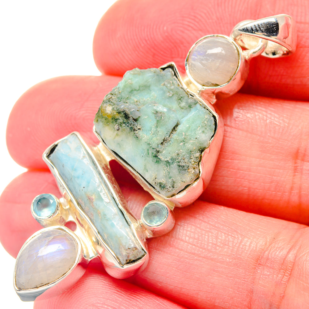 Sterling silver pendant close-up: rough green stone with light blue bar and moonstone discs