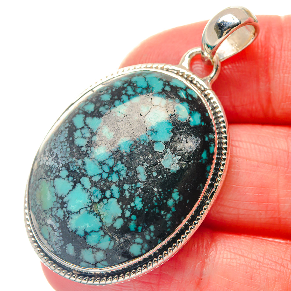 Oval turquoise stone pendant in silver bezel with bail loop, black and blue web