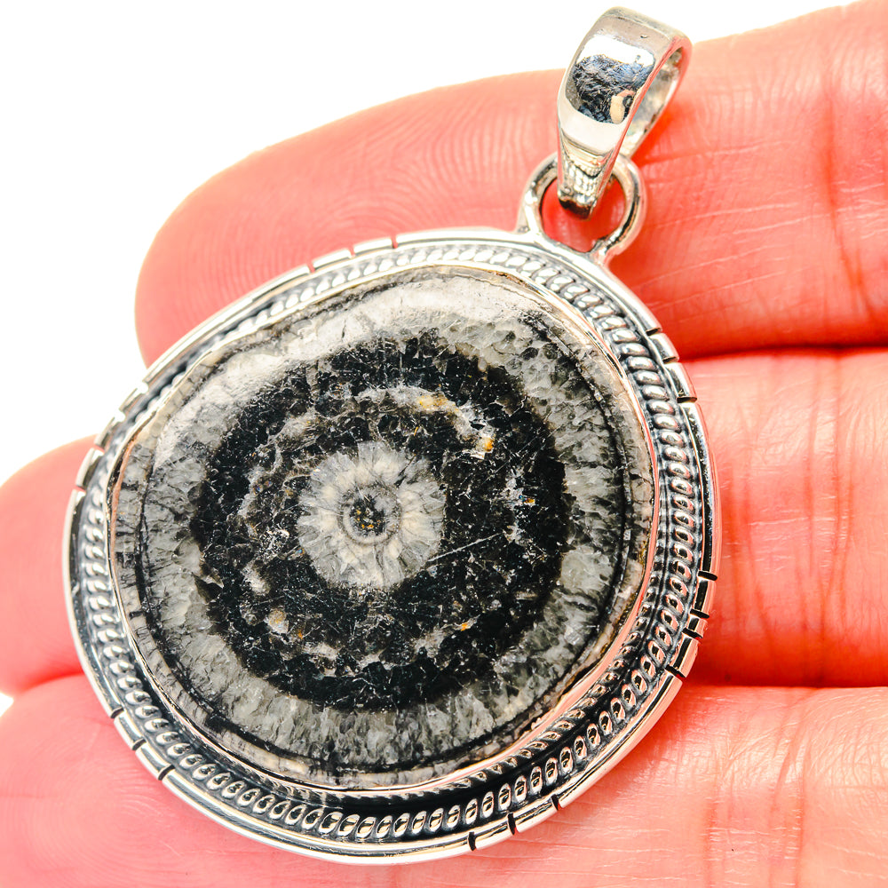 Round sterling silver Evil Eye pendant on bail, close-up view on hand