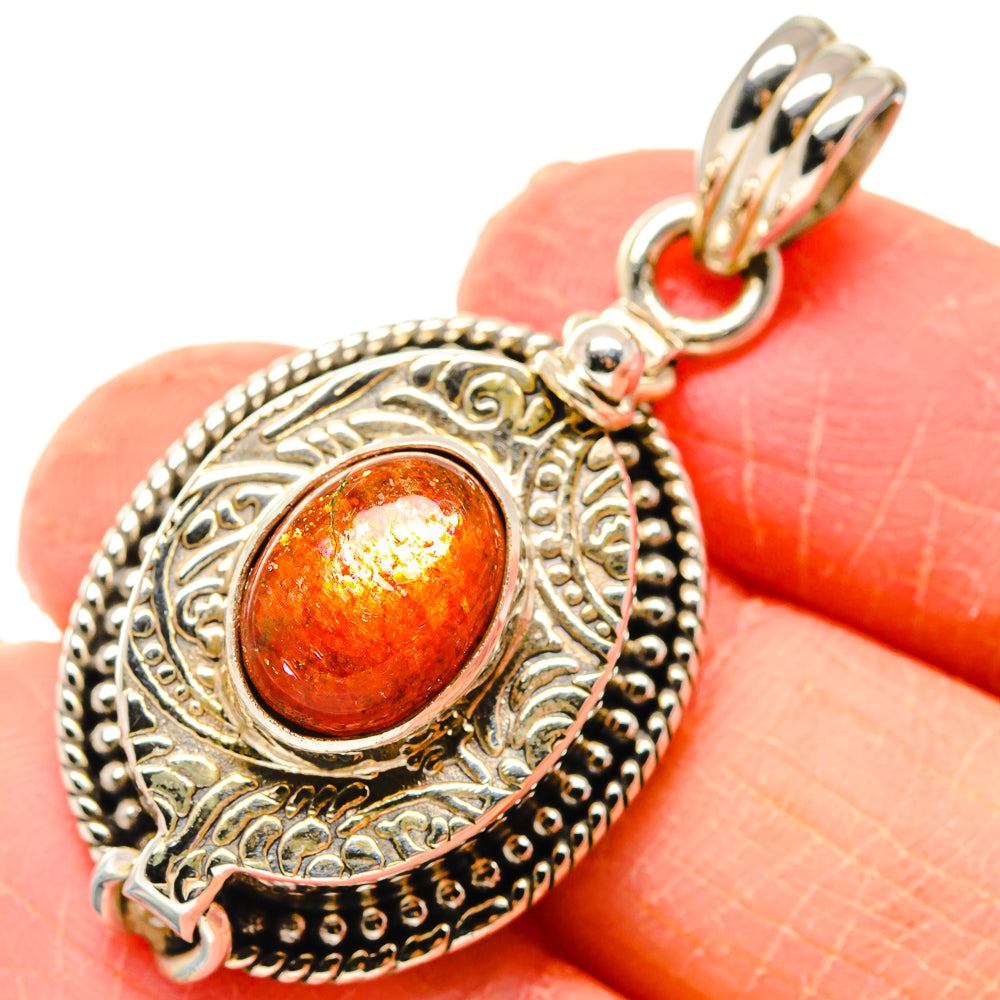 Sterling silver pendant with round orange-red sunstone and ornate filigree edge
