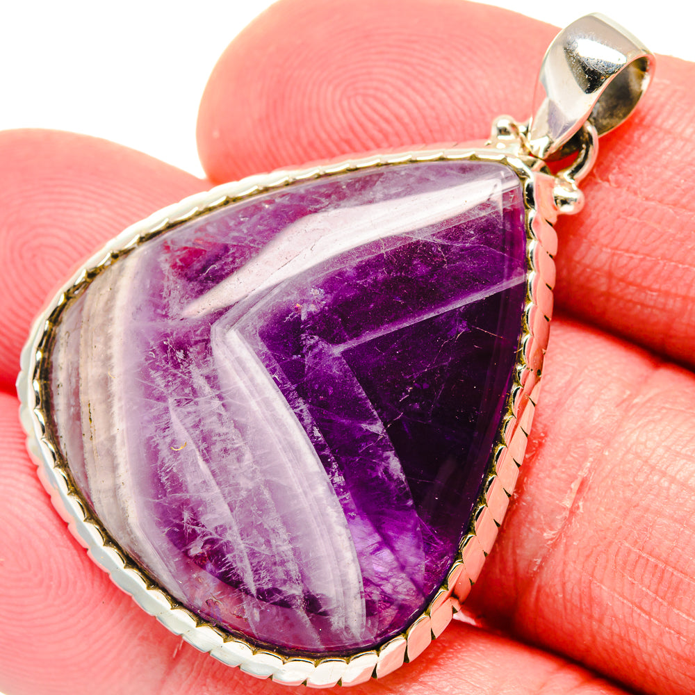 Amethyst teardrop pendant with purple gemstone cabochon in silver bezel and bail.