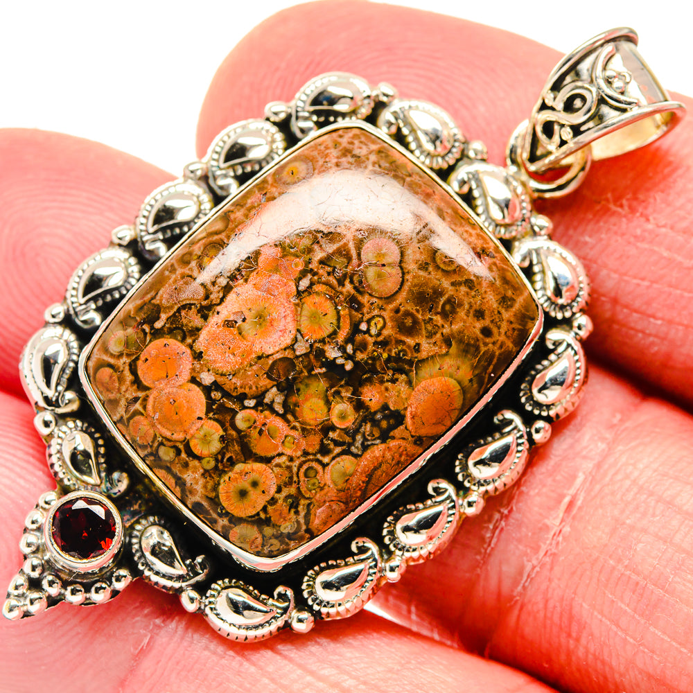 Poppy jasper oval pendant with red garnet accents, ornate silver frame on finger