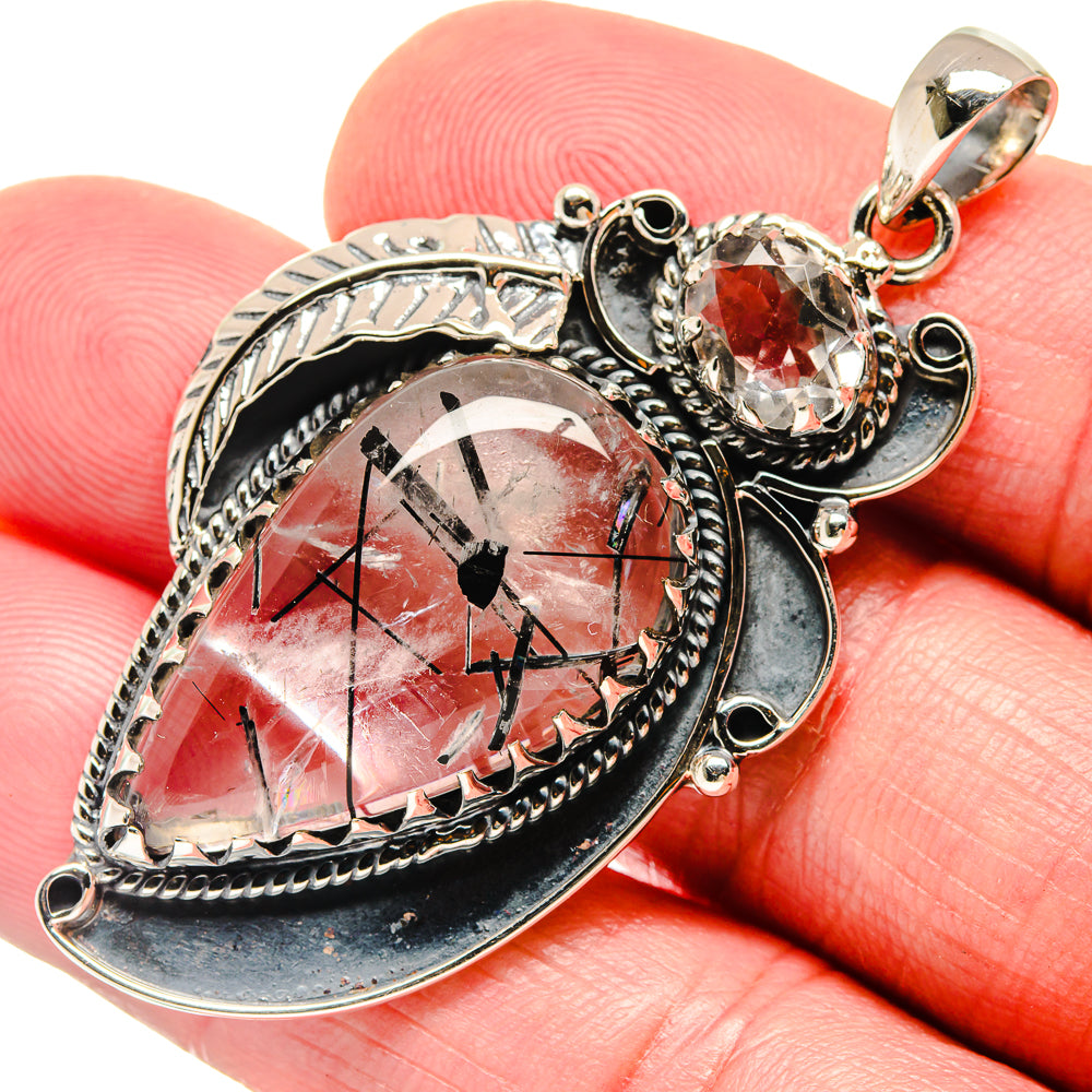 Heart-shaped silver-tone pendant with red faceted gemstone and ornate bezel