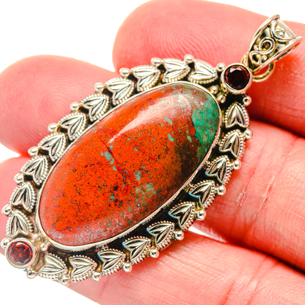 Sterling silver garnet pendant close-up, oval red-orange stone with leaf bezel and red accents