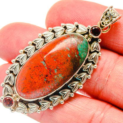 Sterling silver garnet pendant close-up, oval red-orange stone with leaf bezel and red accents