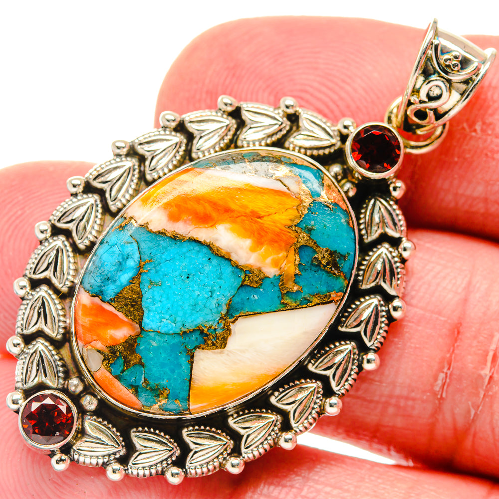 Turquoise gemstone oval pendant with red garnet accents in silver leaf bezel