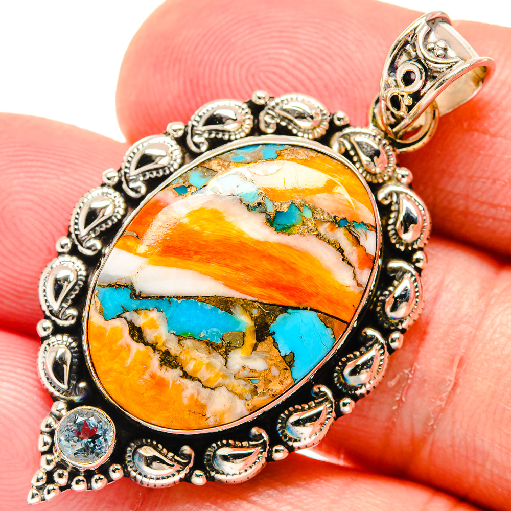 Close-up oval turquoise-orange cabochon pendant in silver filigree with blue topaz-style stones