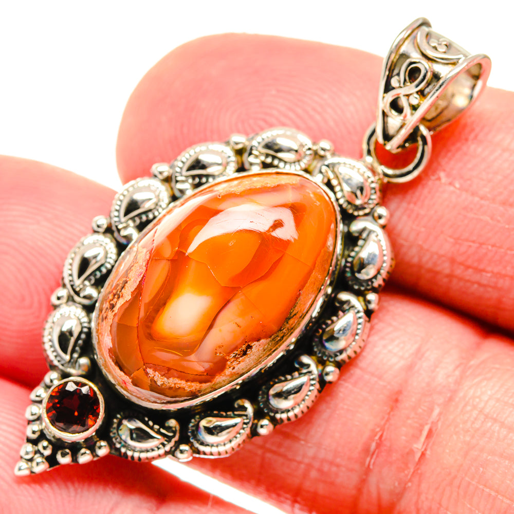 Sterling silver oval fire opal pendant with round garnet accents, close-up on bail