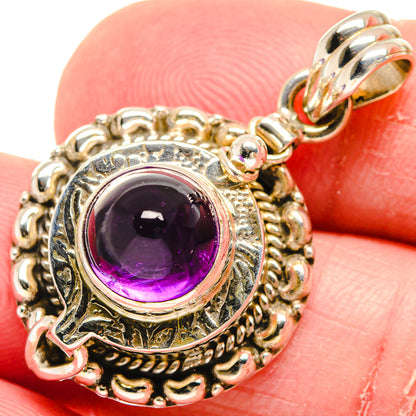 Sterling silver amethyst pendant with ornate circular frame and purple cabochon gemstone