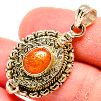 Sterling silver pendant with round orange sunstone cabochon and ornate filigree border