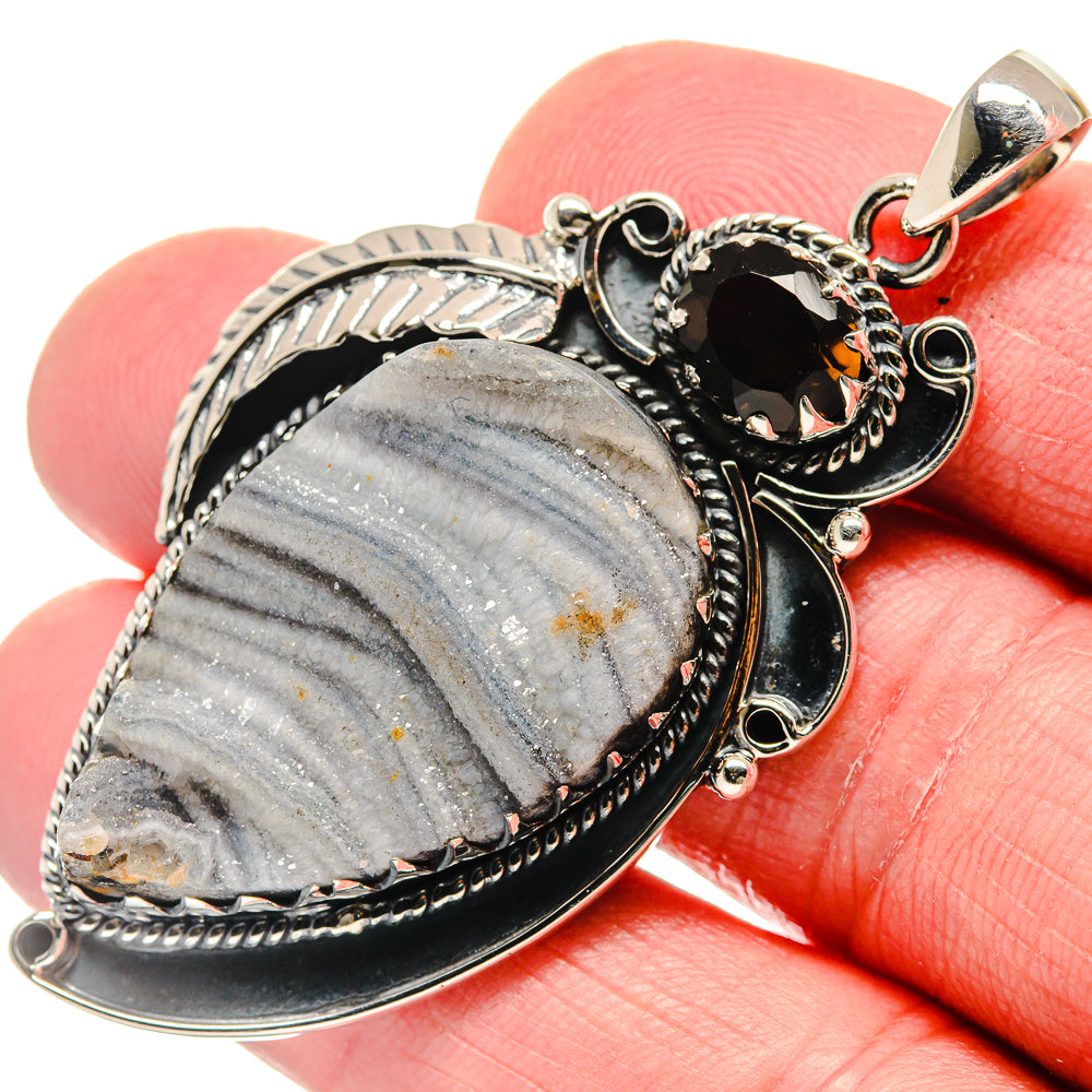 Oval blue-gray druzy stone pendant with silver filigree border, black center, amber facet