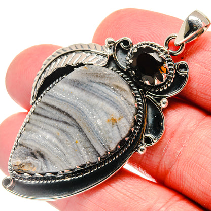 Oval blue-gray druzy stone pendant with silver filigree border, black center, amber facet