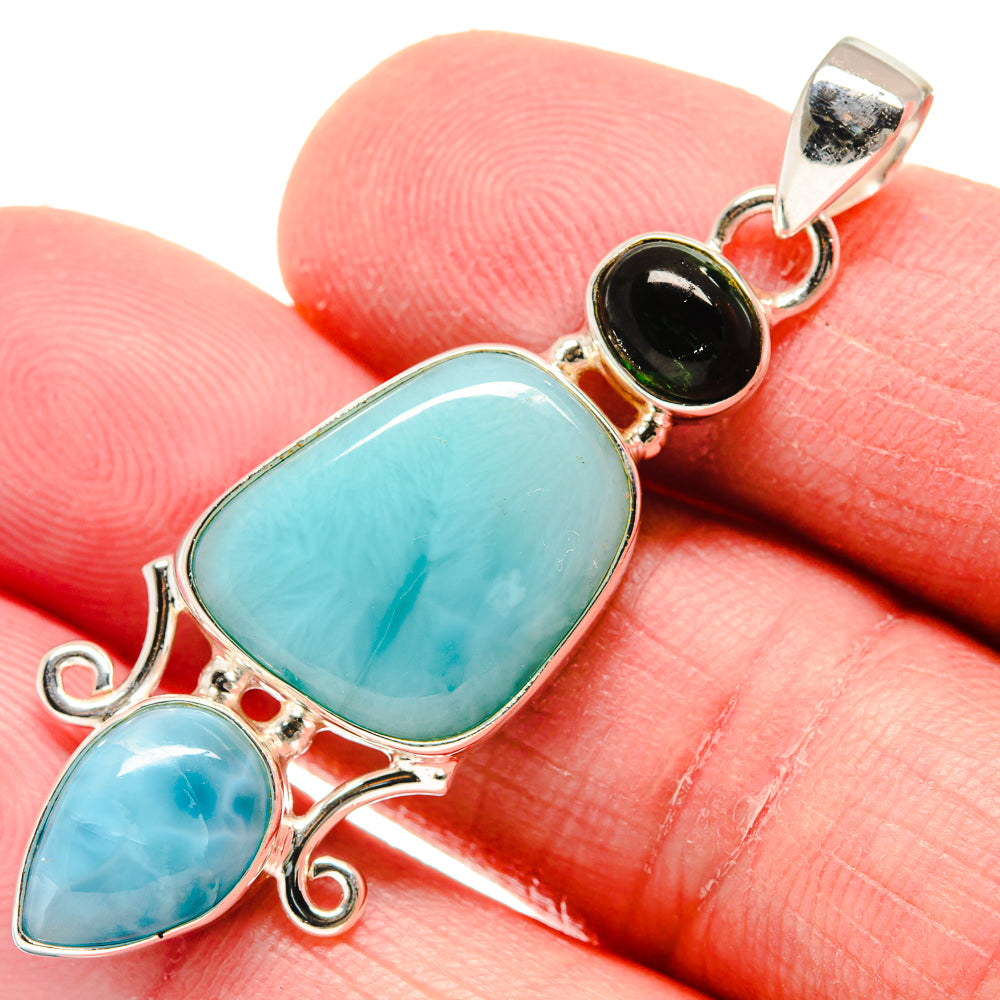 Turquoise gemstone pendant close-up with round black accent and silver bail