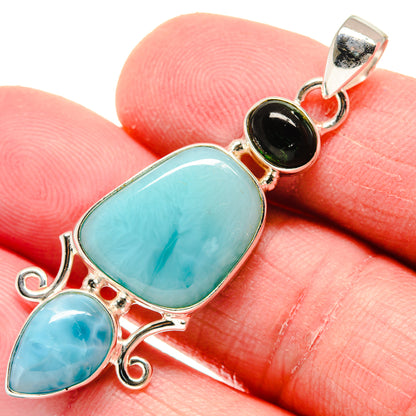 Turquoise gemstone pendant close-up with round black accent and silver bail