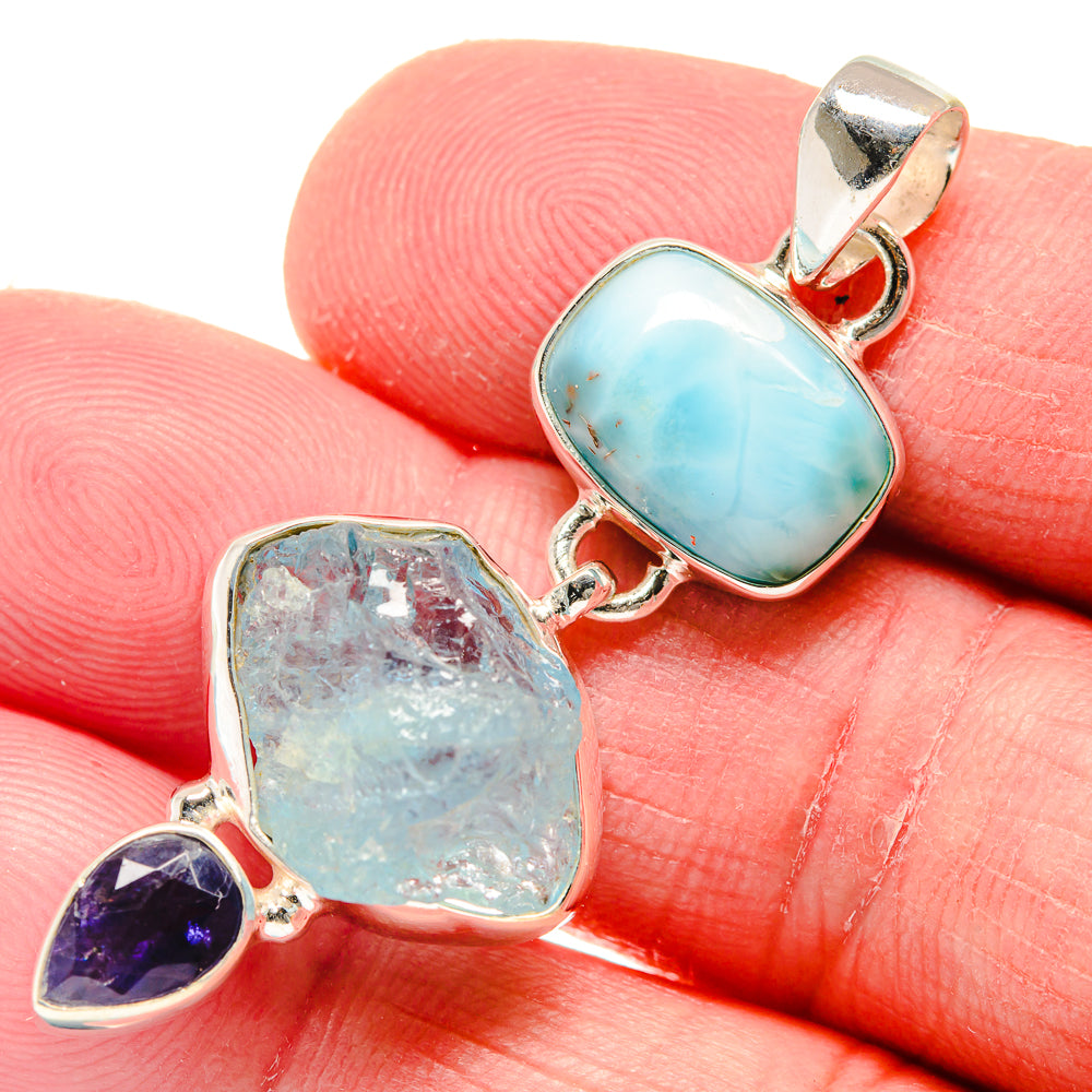Sterling silver gemstone pendant on finger; turquoise oval stone with rough light-blue and purple