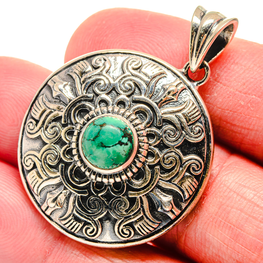 Round silver pendant close-up with teal turquoise cabochon and engraved floral filigree