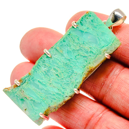 Rough chrysoprase pendant on close-up hands, silver prong setting, bright green
