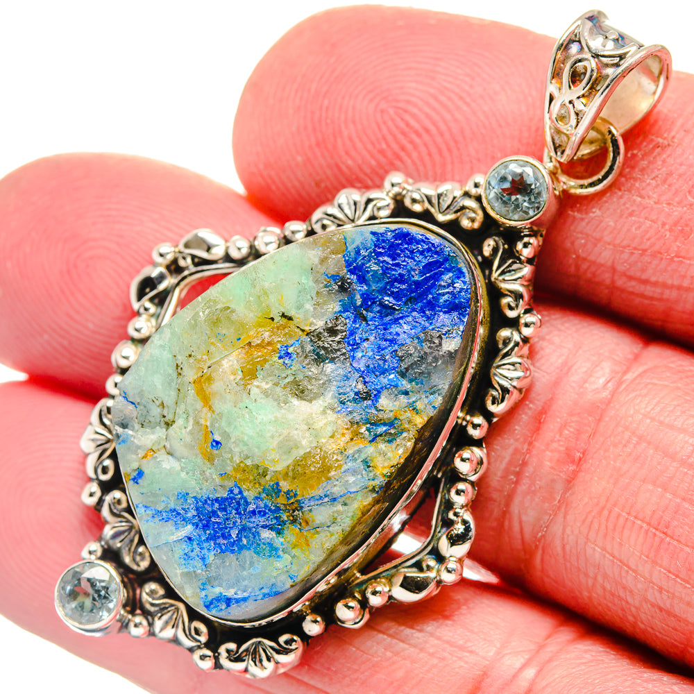 Oval rough stone pendant with blue topaz accents; ornate 925 sterling silver setting