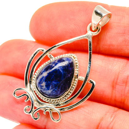 Sodalite teardrop pendant close-up: blue stone set in silver ornate wire loop