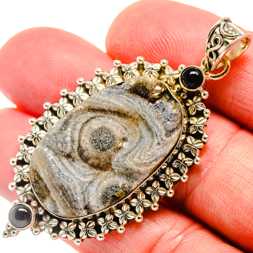 Gold-tone oval druzy stone pendant with black onyx accents and ornate floral border