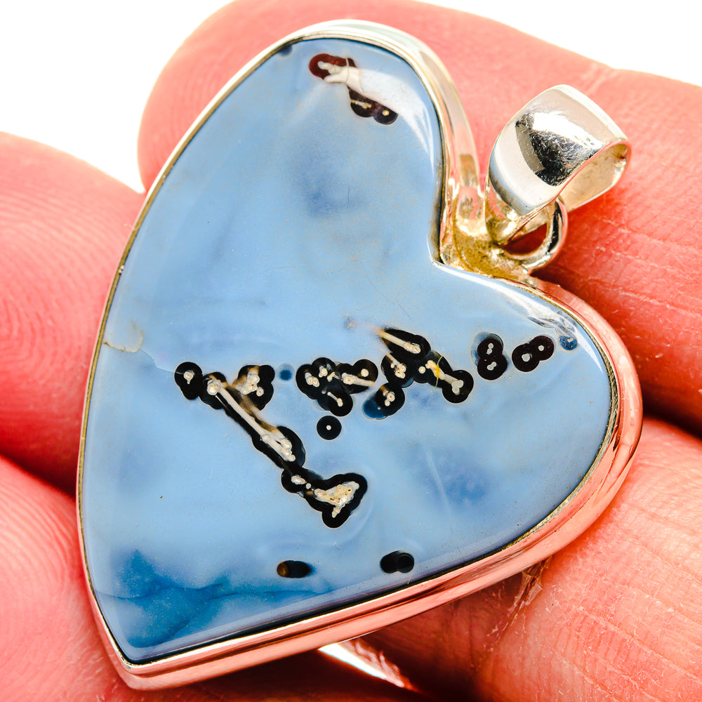 Blue opal heart pendant with 925 sterling silver frame and bail, viewed on fingertip