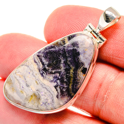 Teardrop stone pendant close-up with purple and black marbling in polished silver bezel