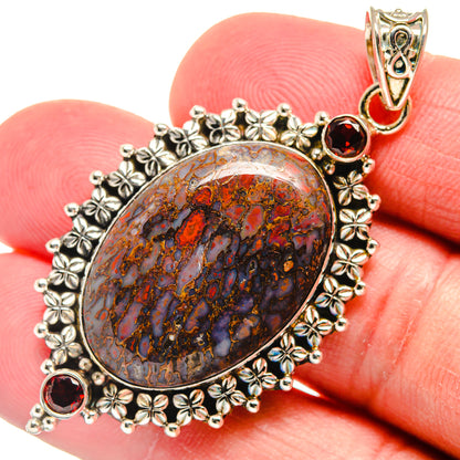 Close-up oval 925 sterling silver pendant with marbled dinosaur-bone pattern and red garnets