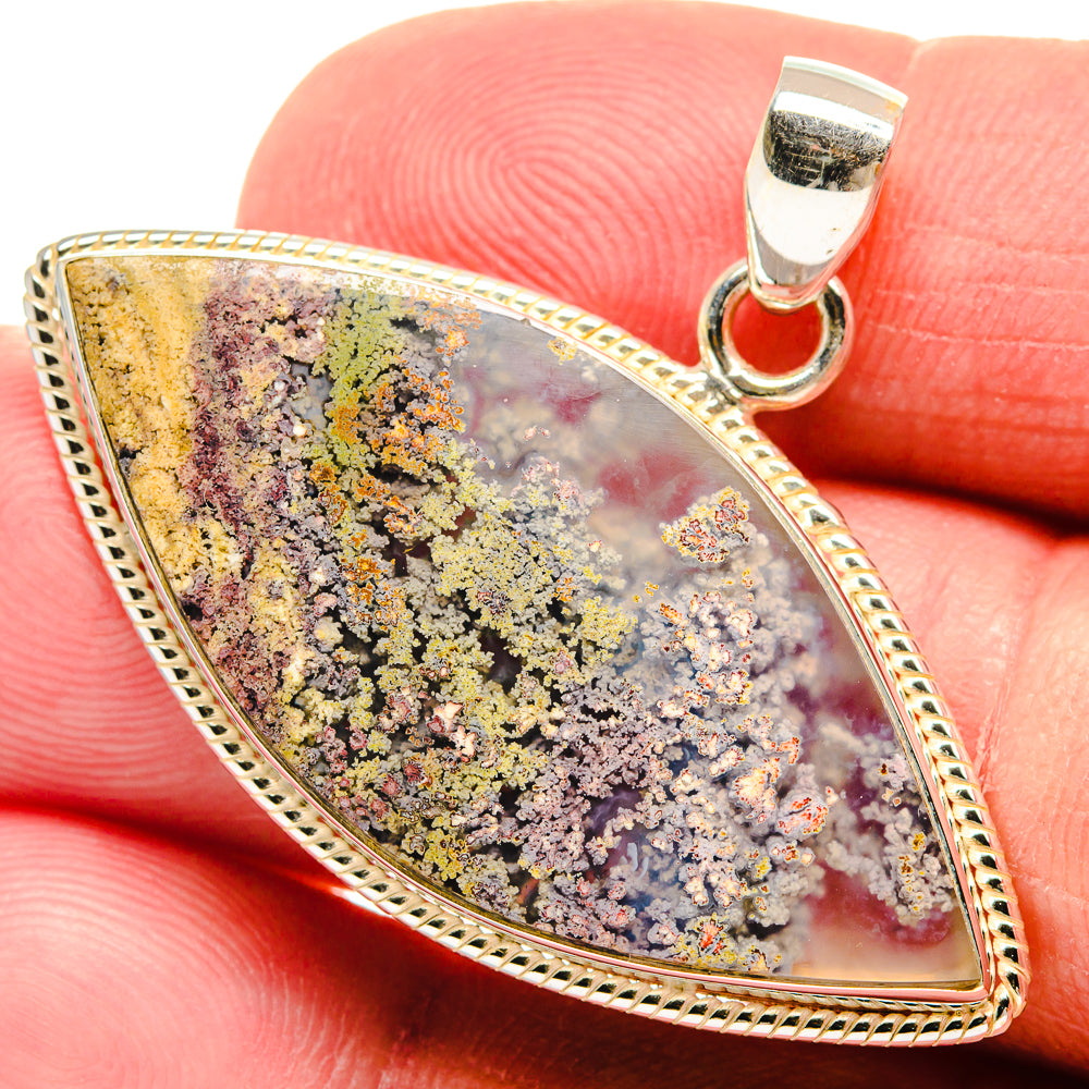 Teardrop plume agate pendant with speckled yellow, purple, and gray stone in silver setting.
