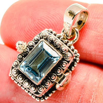 Sterling silver blue topaz pendant close-up with scrollwork bezel and hoop bail
